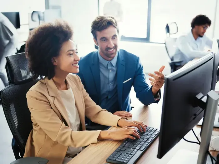 Colleagues collaborating at a desktop computer in a bright office, reviewing options and services in the directory